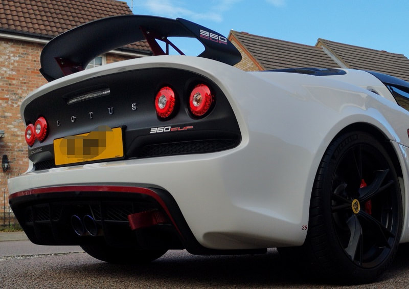 A white Lotus Exige 360 Cup on a driveway with the blue sky as background.